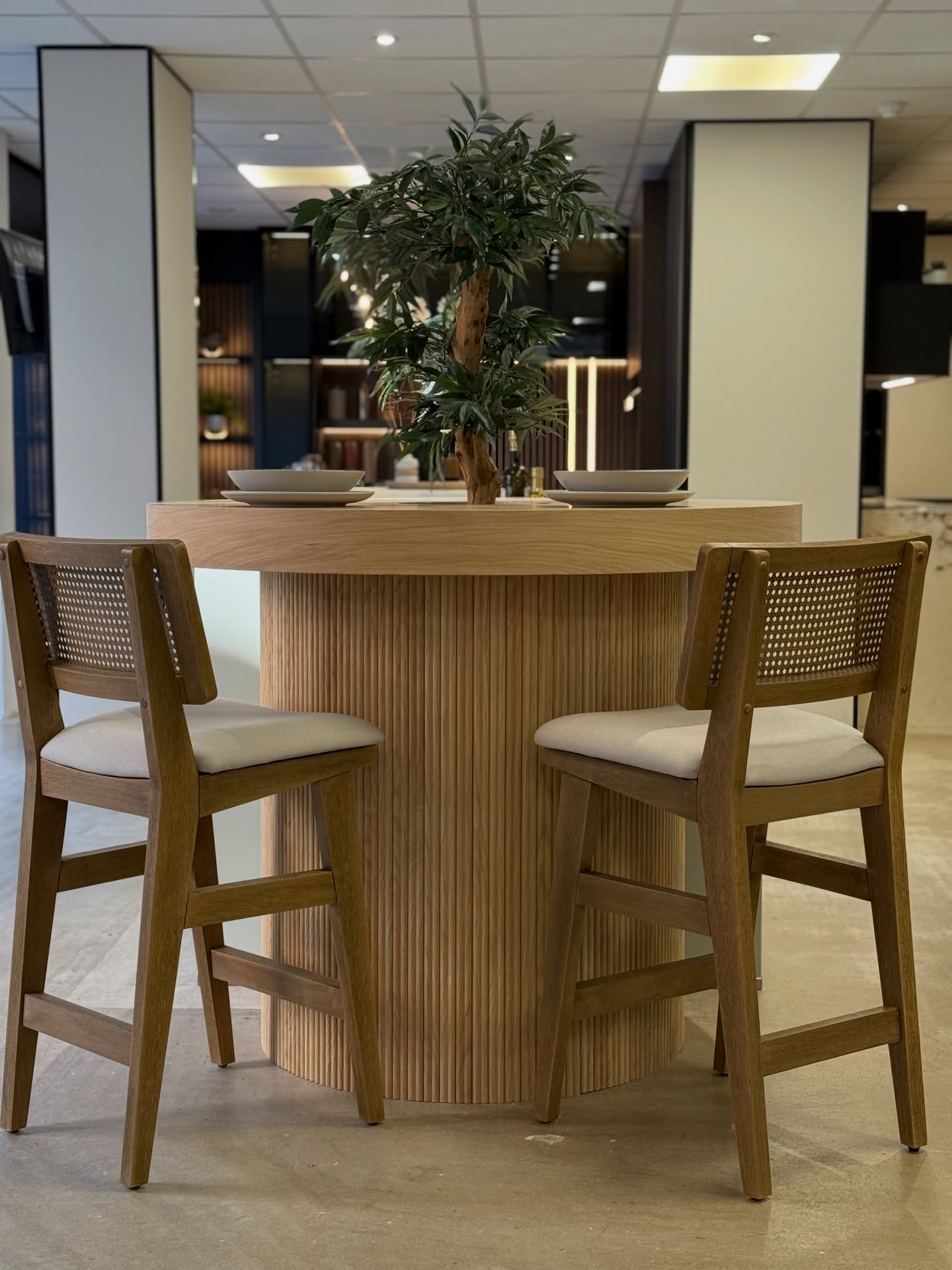 Chichester showroom display with a rounded timber breakfast bar and woven-back chairs