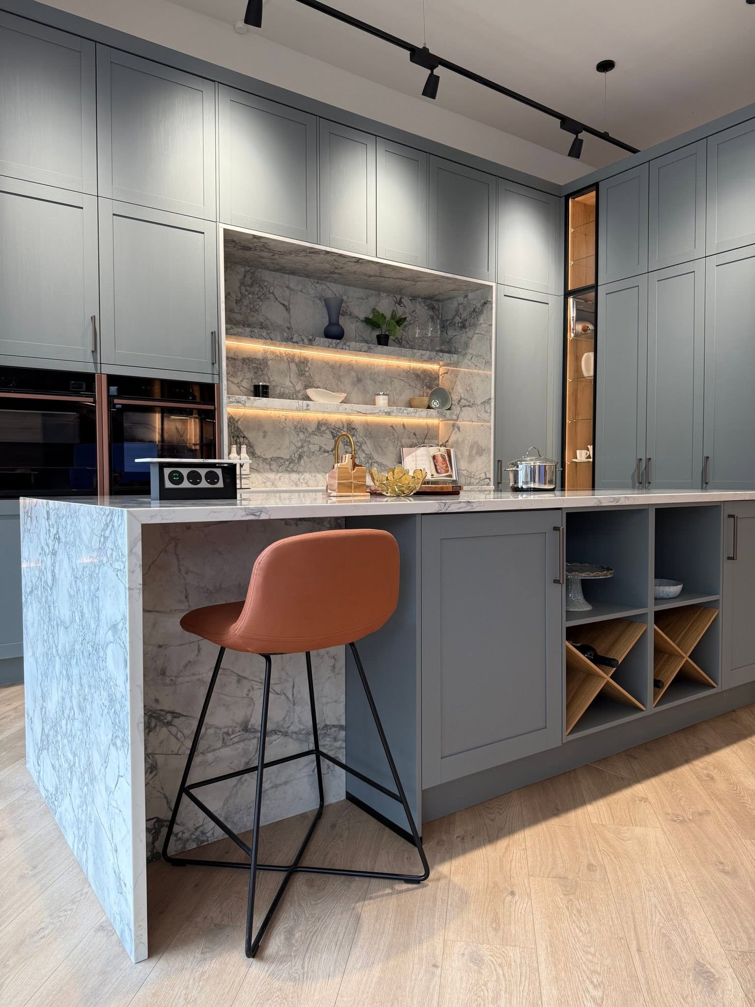 Petersfield kitchen display with grey Shaker cabinetry, marble-effect island and illuminated shelving